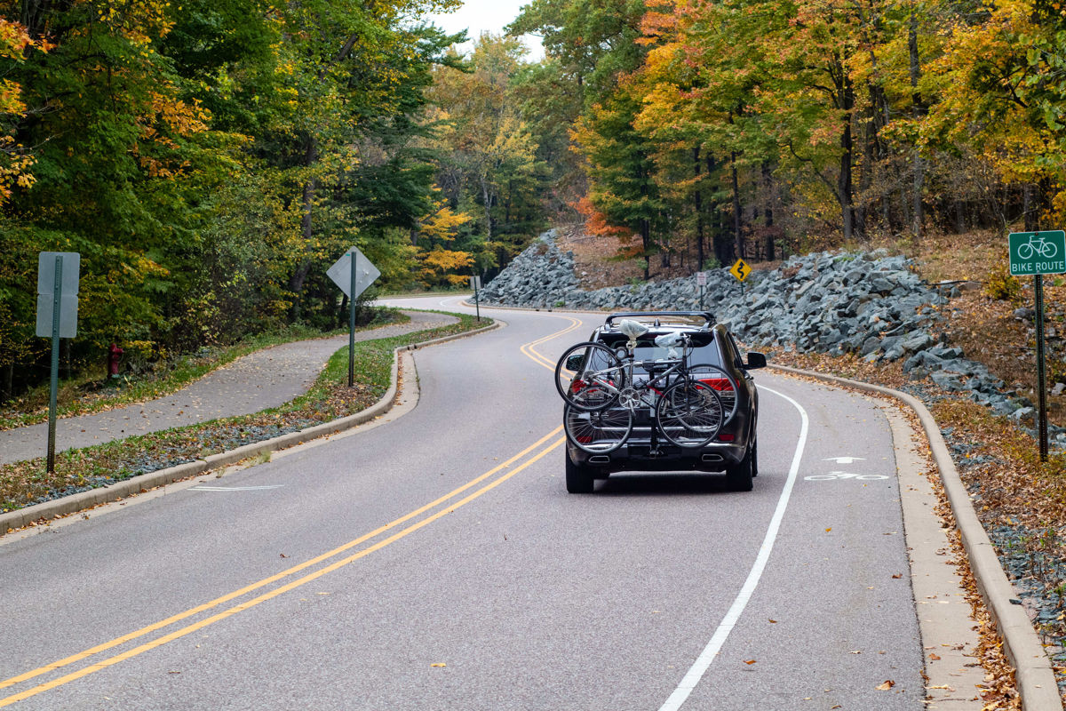 suv with bikes attached driving down fall road
