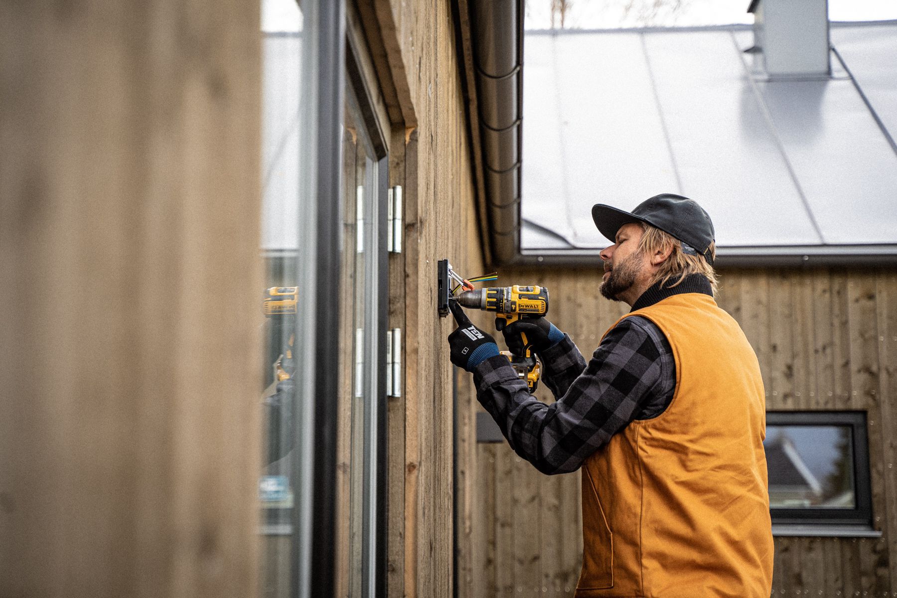 man in orange vest installing something on an exterior of a building