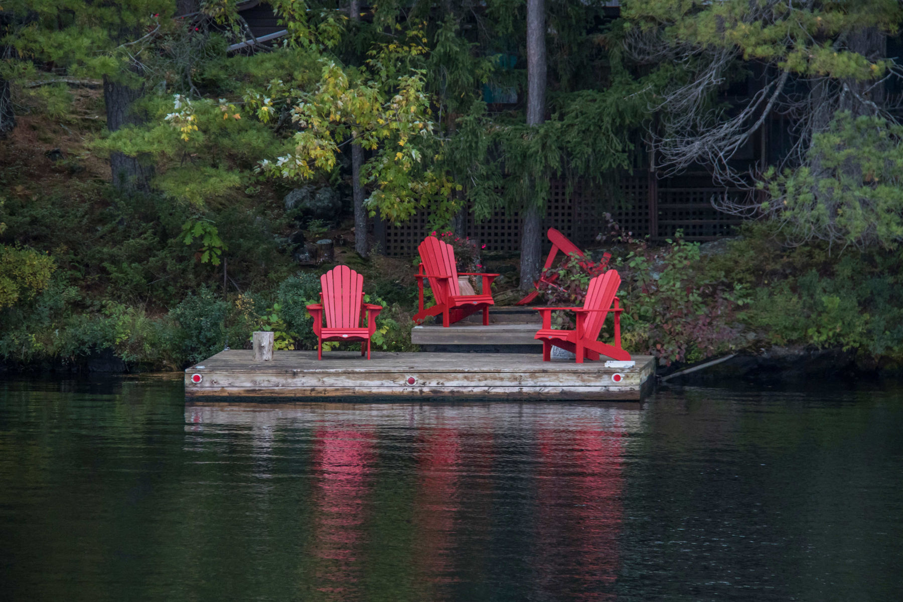 two red adirondack chairs on a dock